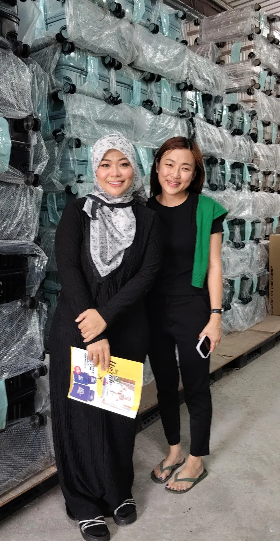 Two women in the KIYO warehouse between racks of wrapped cases